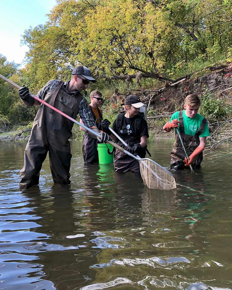 students in waders working in stream
