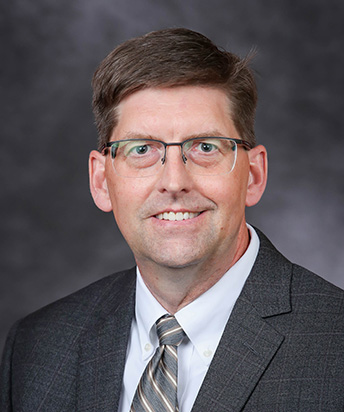 Professional headshot photo of David Pierce against gray backdrop