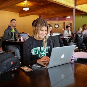 Student studying on laptop in coffeehouse