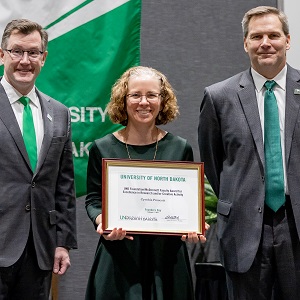 Prescott holds certificate; President Armacost and Provost Link stand with her