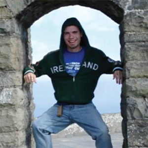 Kenneth Granle standing in a stone window with "Ireland" hoodie on in front of landscape