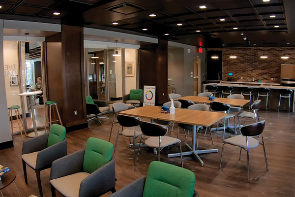 Wide angle shot of the CALL cafe space with tables, chairs, and kitchenette counters
