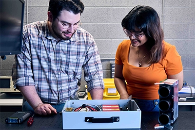Two students at laser table inspecting equipment