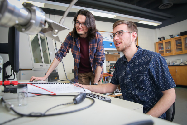 Two students in front of computer screen in lab
