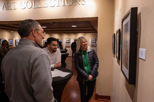 An art gallery with several people looking at photographs on the wall
